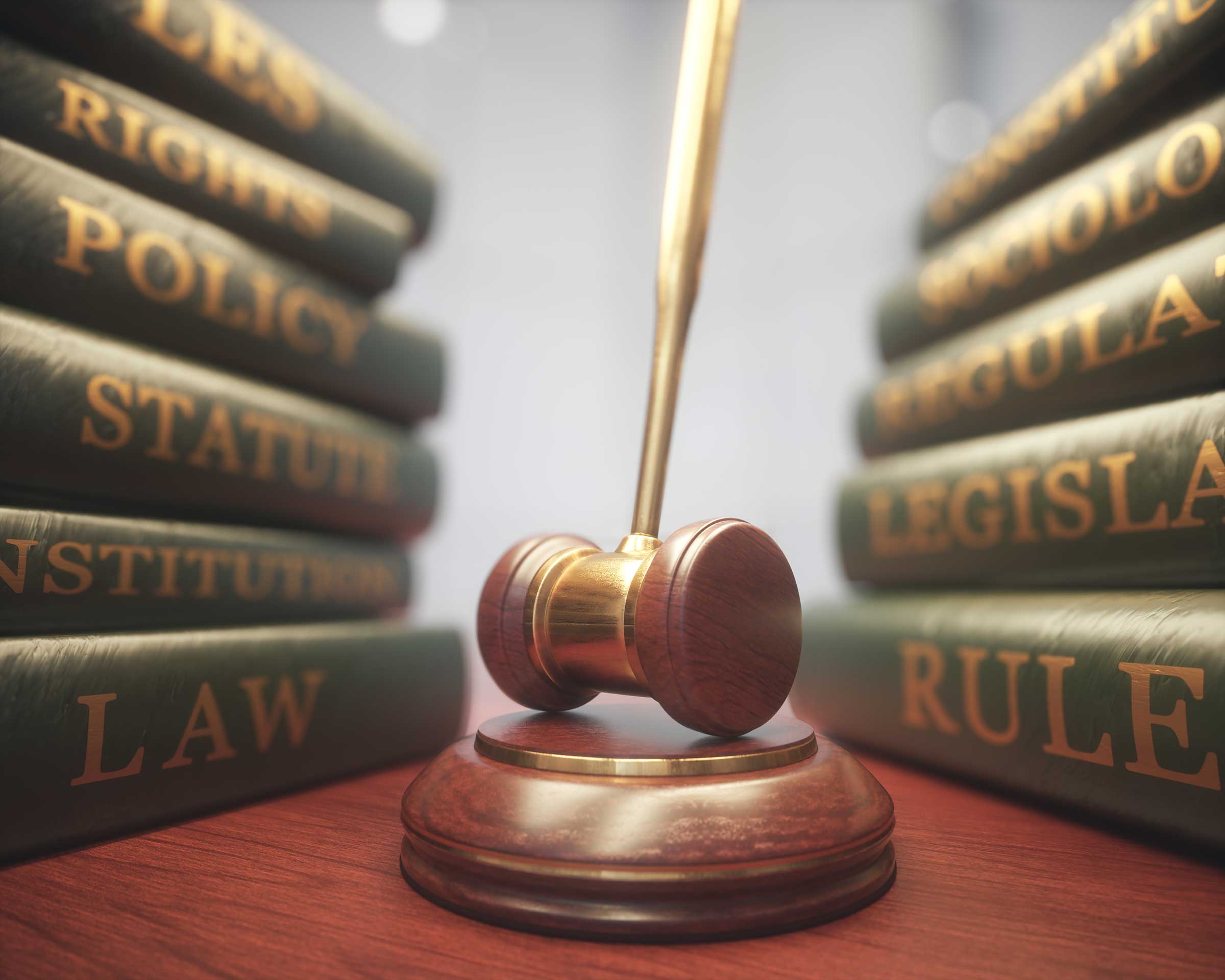 A wooden gavel sitting in front of many law books.